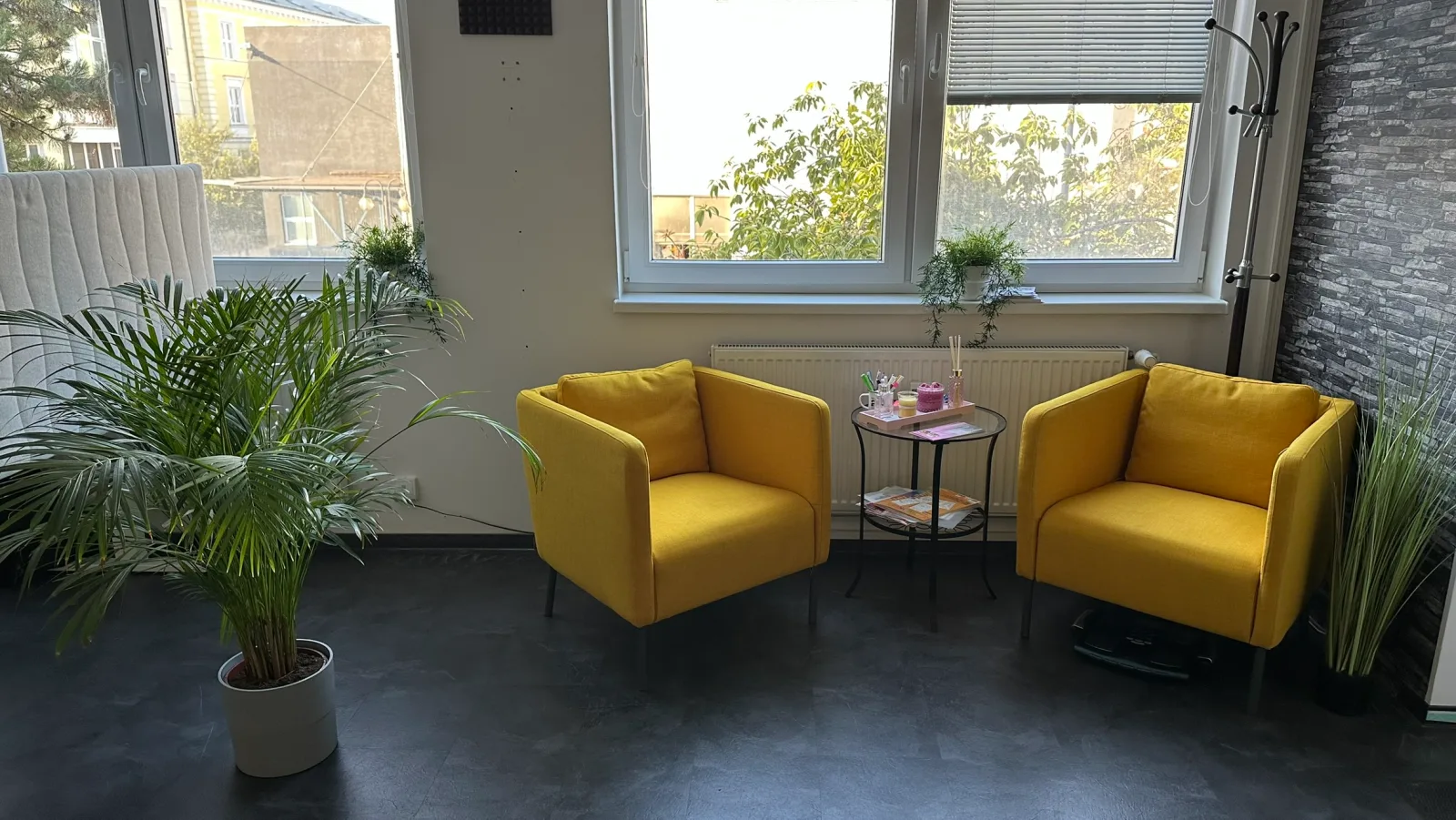 Dvě žlutá křesla, stolek a zeleň u oken v relax zóně